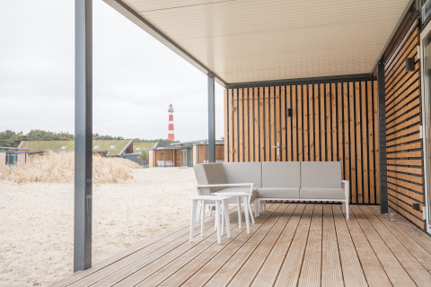 Strandterras met moderne zit en uitzicht op vuurtoren bij Sea Lodges Ameland 3 in Nederland.