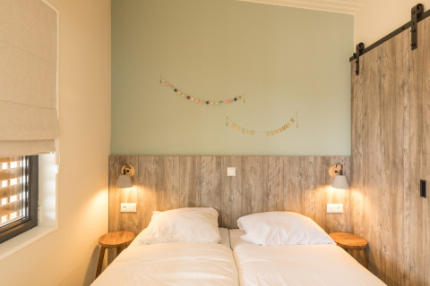 Slaapkamer met twee enkele bedden, houten accenten en zachte verlichting bij Sea Lodges Ameland 3, Nederland.