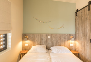 Slaapkamer met twee enkele bedden, houten accenten en zachte verlichting bij Sea Lodges Ameland 3, Nederland.