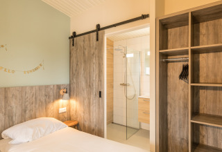 Slaapkamer in Sea Lodges «Ameland 3» in Nederland met houten afwerking, schuifdeur en badkamer.