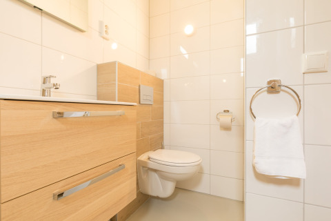 Moderne badkamer in Sea Lodges «Ameland 3», Nederland, met hangtoilet en licht houten badkamermeubel.
