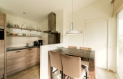 Moderne keuken en eetruimte met houten tafel in Holiday park «Boomhiemke 7» in Nederland.