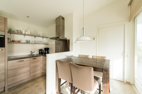 Cocina y comedor modernos con mesa de madera en Holiday park «Boomhiemke 7» en los Países Bajos.