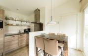 Modern kitchen and dining area with wooden table at Holiday park «Boomhiemke 7» in the Netherlands.