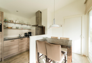 Cocina y comedor modernos con mesa de madera en Holiday park «Boomhiemke 7» en los Países Bajos.