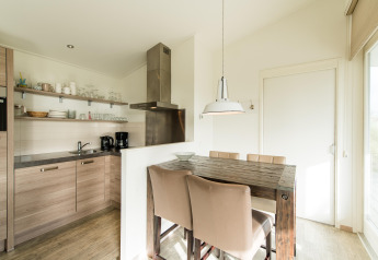 Modern kitchen and dining area with wooden table at Holiday park «Boomhiemke 7» in the Netherlands.