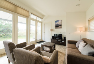 Helles Wohnzimmer im Holiday Park Boomhiemke 7 in den Niederlanden mit modernen Möbeln und Fenstern.