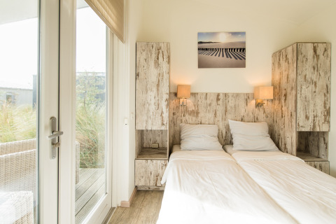 Bright bedroom at Holiday Park Boomhiemke 7, Netherlands, featuring twin beds and rustic wooden cabinets.