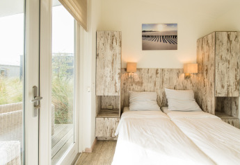 Bright bedroom at Holiday Park Boomhiemke 7, Netherlands, featuring twin beds and rustic wooden cabinets.