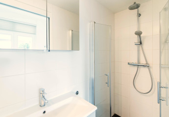 Heldere, moderne badkamer met douche en wastafel in Holiday park «Boomhiemke 7» in Nederland.