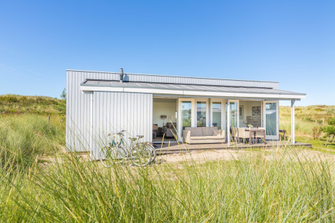 Lodge moderno en Holiday park «Boomhiemke 7» en Países Bajos, rodeado de dunas y vegetación natural.