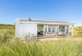 Modern lodge at Holiday park «Boomhiemke 7» in the Netherlands set amongst dunes and grassy landscape.