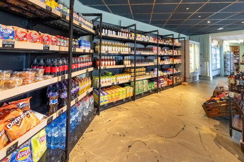 Negozio di lodge accogliente con scaffali pieni di snack, bibite, acqua e generi alimentari vari.