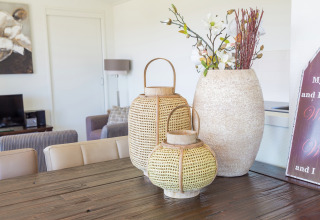Geflochtene Laternen und Blumenvase auf Holztisch im Ferienpark Boomhiemke 7, Niederlande, dekoriert.