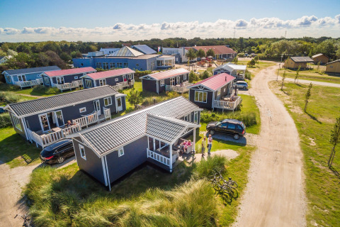Ferieparken Boomhiemke 6 i Holland, med blå hytter, grønne omgivelser og besøgende på terrassen.