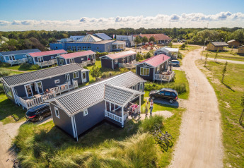 Ferieparken Boomhiemke 6 i Holland, med blå hytter, grønne omgivelser og besøgende på terrassen.