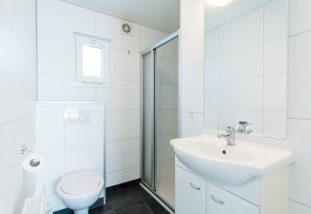 Lyst og moderne badeværelse med bruseniche, toilet og håndvask på Holiday park «Boomhiemke 6» i Holland.