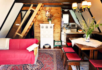 Knus lodge-interieur in Oostenrijk met houten muren, rode bank, eettafel en een ladder naar de slaapzolder.