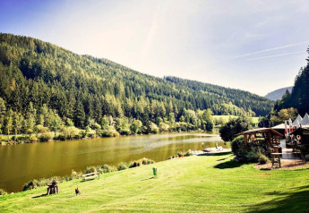 Mooi uitzicht op het Trabochersee-meer met omliggende heuvels en de Ferienhütte Trabochersee-lodge, Oostenrijk.