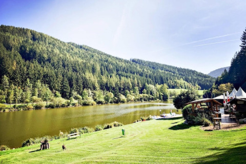 Smuk udsigt over Trabochersee-søen med grønne bakker og feriehus, Ferienhütte Trabochersee, i Østrig.