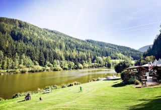 Smuk udsigt over Trabochersee-søen med grønne bakker og feriehus, Ferienhütte Trabochersee, i Østrig.