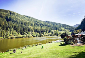 Vista pintoresca del lago Trabochersee rodeado de colinas verdes y la cabaña Ferienhütte Trabochersee en Austria.