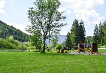 Aire de jeux et prairies verdoyantes à Ferienhütte Trabochersee, entourées de montagnes en Autriche.