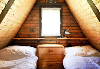 Cozy wooden room at Ferienhütte Trabochersee, Austria, with two beds, small dresser, and window.