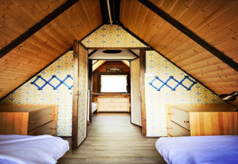 Cozy lodge room with slanted wooden ceilings, twin beds, and dressers at Ferienhütte Trabochersee, Austria.