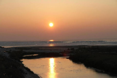 Sonnenuntergang über dem Wasser im Holiday Park «Boomhiemke 6» in den Niederlanden mit Flussreflexion.