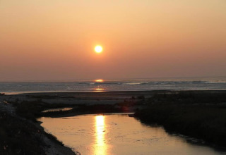 Sunset over the water at Holiday park «Boomhiemke 6» in the Netherlands with a river reflection view.