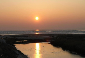 Atardecer sobre el agua en Holiday park «Boomhiemke 6» en los Países Bajos, reflejado en un tranquilo río.