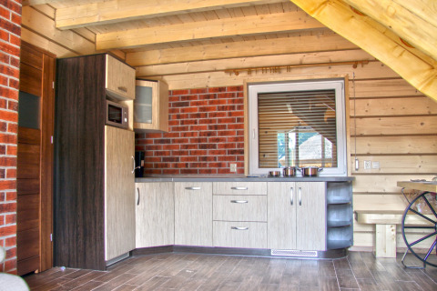 Cucina moderna in chalet di legno con parete in mattoni, finestra e pentole nel Holiday home «Maryna».