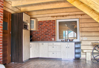 Cocina moderna de chalet de madera con pared de ladrillo, armarios y ollas en la encimera en Holiday home «Maryna».
