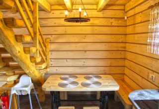Interno in legno di uno chalet con tavolo da pranzo, scala e lampada al Holiday home «Maryna» in Germania.