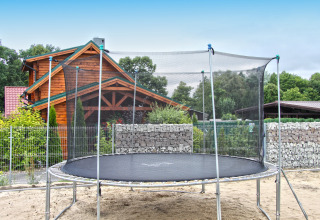 Grande trampolino con rete di sicurezza in giardino davanti allo chalet Holiday home «Maryna», Germania.