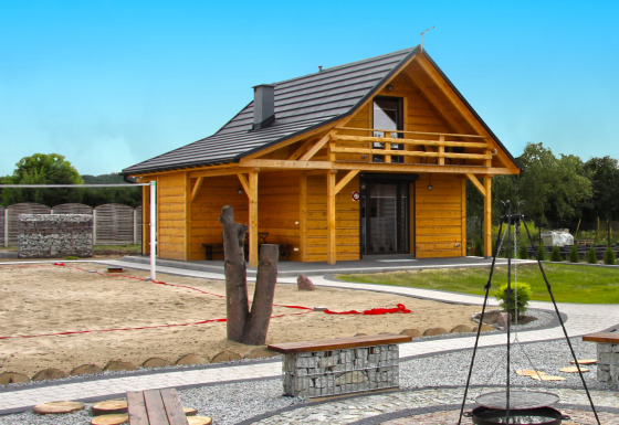 Holiday home Maryna: Chalet de madera con balcón, cancha de arena y zona de fogata en un entorno ajardinado.