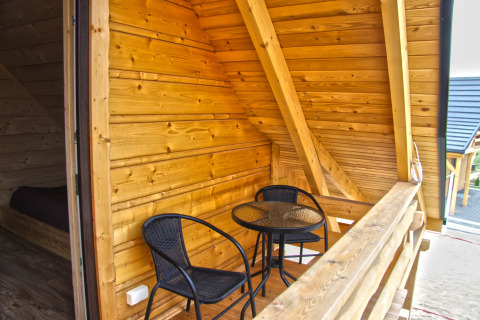 Træveranda med to sorte stole og et bord på Holiday home «Maryna» chalet i Tyskland, hyggelig atmosfære.