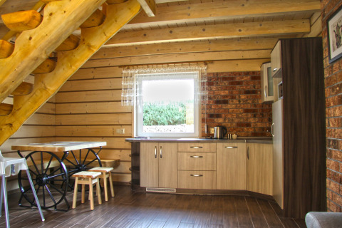 Innenansicht des Ferienhauses Maryna in Deutschland mit Holztreppe, Küche und Esstisch mit Wagenrädern.