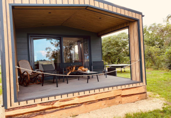 Cabaña de vacaciones de madera con terraza cubierta, muebles, hamaca y perro en Nowe Warpno, Alemania.