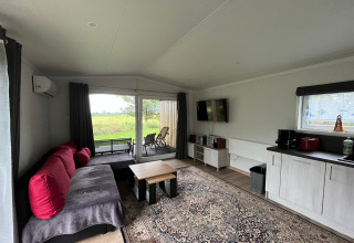 Interior de la casa vacacional Inselblick en Nowe Warpno, Alemania, con sofá, alfombra, TV y terraza.