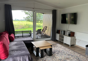 Stue i Holiday home Inselblick i Nowe Warpno, Tyskland, med sofa, tv, gulvtæppe og udsigt til natur.