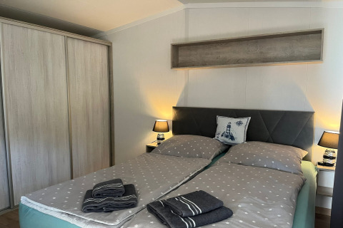 Cozy bedroom with double bed, gray dotted bedding, lamps, and wardrobe at Holiday home 'Inselblick'.