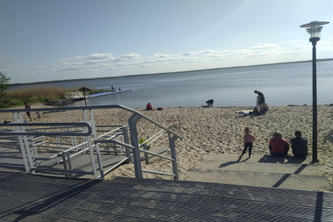 Beach by Holiday home Inselblick in Nowe Warpno, Germany, with people, a boardwalk, and calm water.
