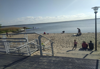 Beach by Holiday home Inselblick in Nowe Warpno, Germany, with people, a boardwalk, and calm water.