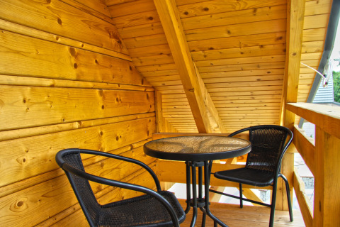 Balcon en bois avec deux chaises noires et une table ronde, chalet Holiday home «Maryna» en Allemagne, journée ensoleillée.