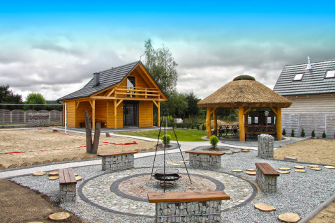 Außenbereich des Holiday home «Maryna» in Deutschland mit Holzhäusern, Feuerstelle und Sitzbänken.