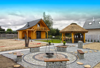 Zona exterior de Holiday home «Maryna» en Alemania con cabañas de madera, fogata y bancos.