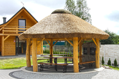 Holzchalet und reetgedeckte Gartenlaube mit Sitzgelegenheiten bei Holiday home «Maryna» in Deutschland.