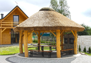 Holzchalet und reetgedeckte Gartenlaube mit Sitzgelegenheiten bei Holiday home «Maryna» in Deutschland.